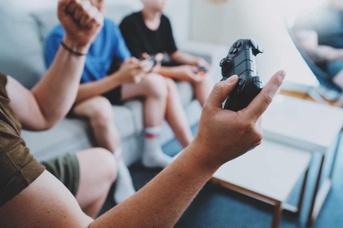 Young bet friends sitting on a sofa in living room and playing video games. Family relaxing time at home concept. Cropped.