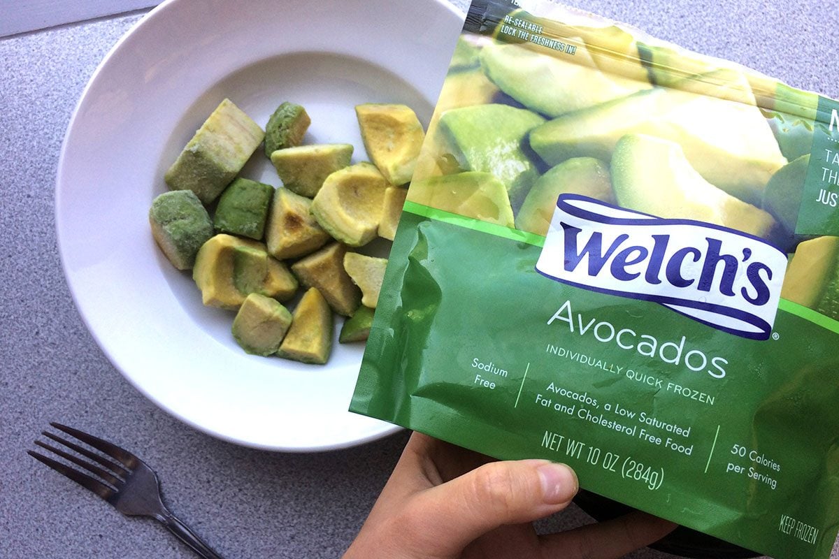 Package of frozen avocados being held up beside a bowl filled with the pieces