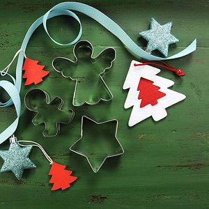 Christmas holiday background with red, white, festive decorations and cookie cutters against a vintage style dark green recycled wood background