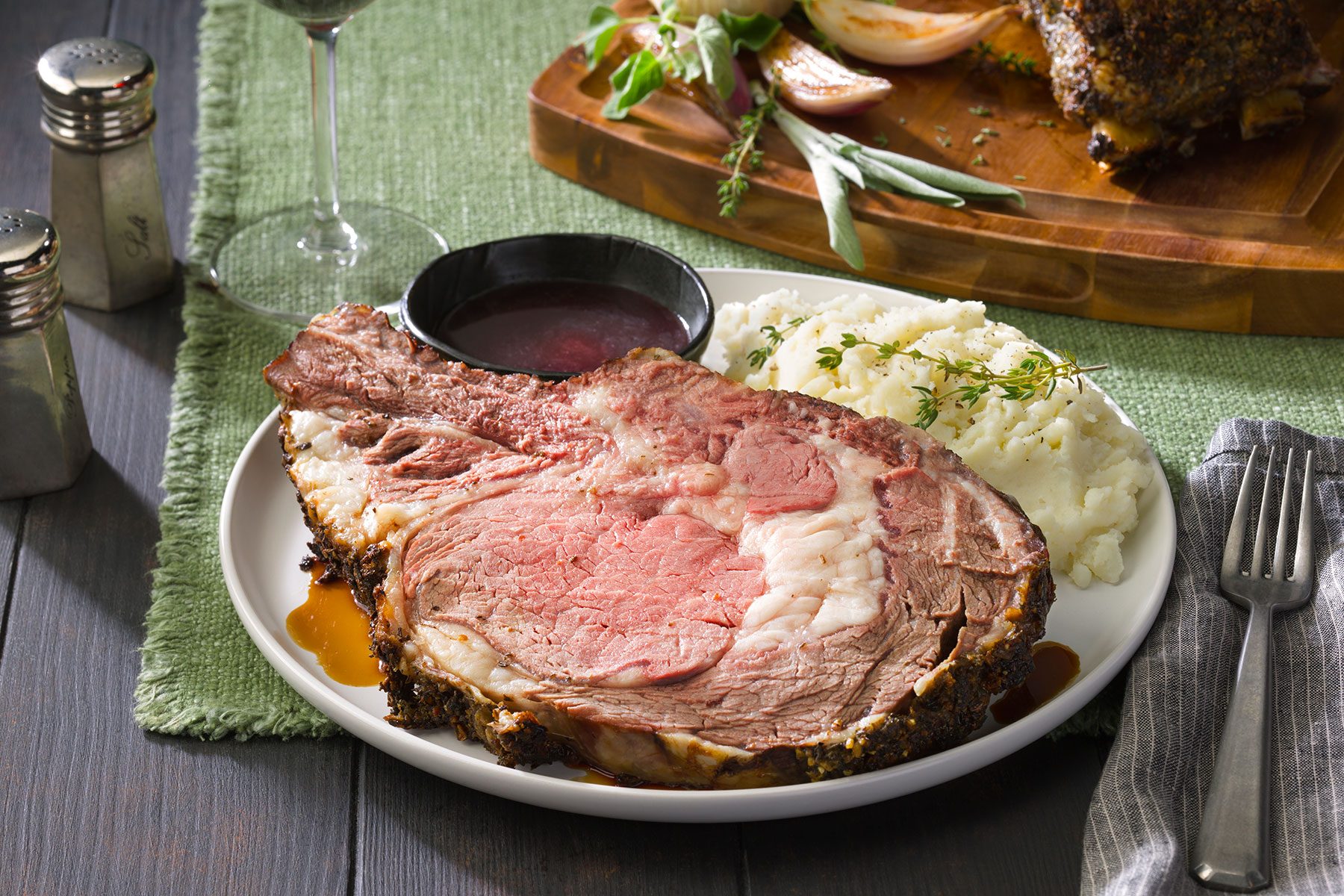 Herb Crusted Prime Rib on Plate with a Glass of Wine and Sauce