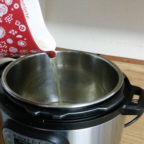 Chicken broth being poured into an instant pot