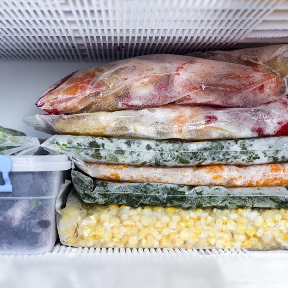 Frozen berries and vegetables in bags in freezer close up; Shutterstock ID 666765940