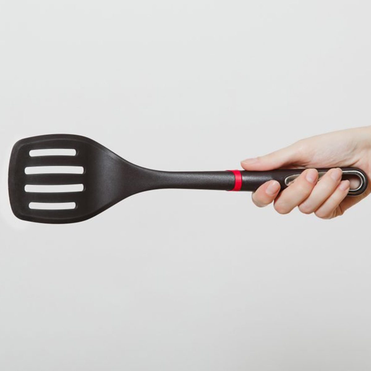 Close up of female hand horizontal holding black spatula isolated on white background.