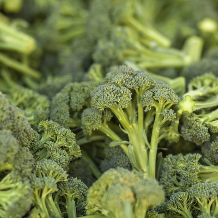 A pile of broccoli stalks at a market.