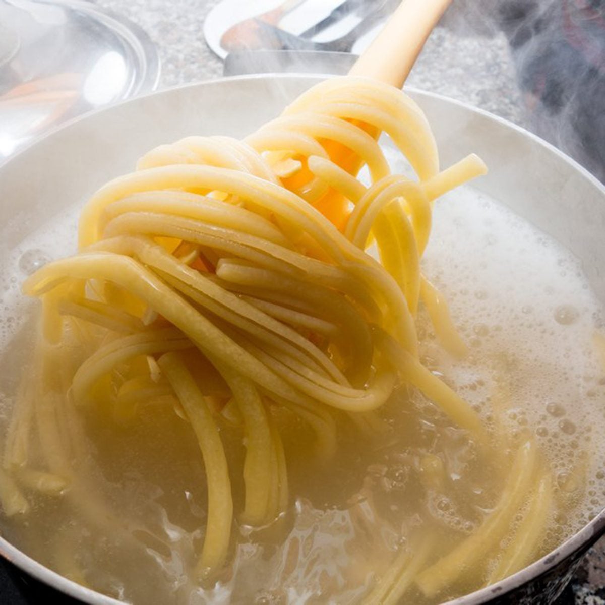 Cooked pasta being pulled from boiling water