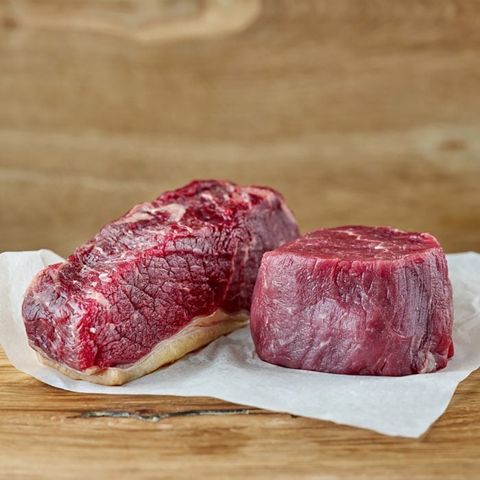 raw strip loin and fillet mignon steak on wooden table