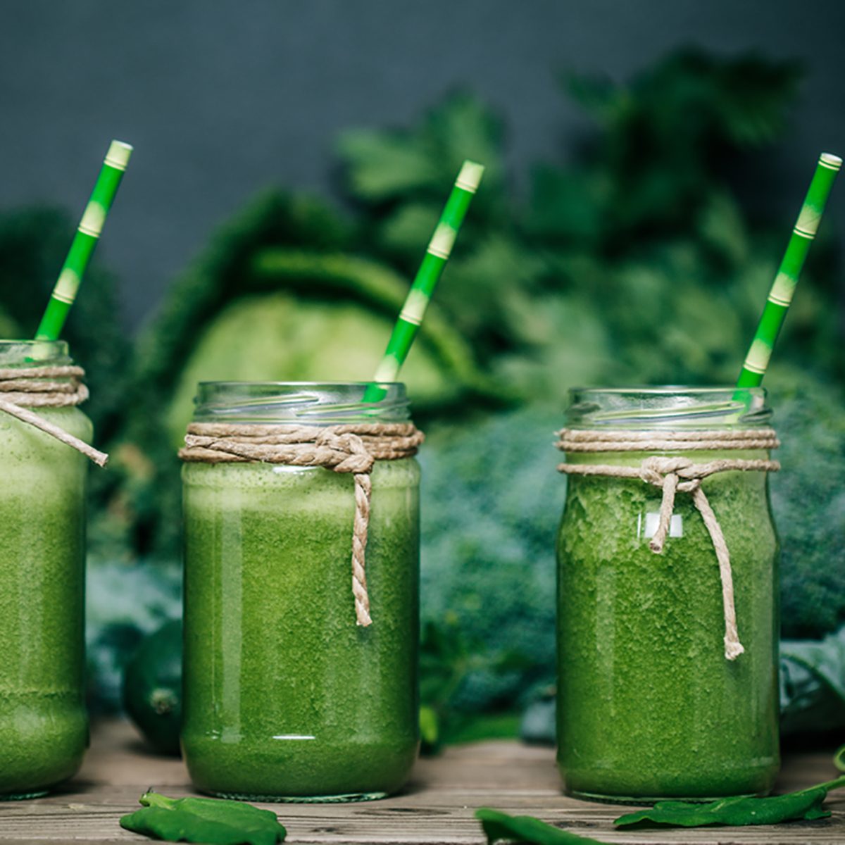 Blended green smoothie with ingredients on wooden table