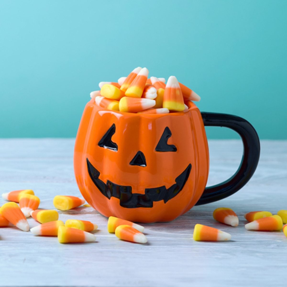 Halloween celebration concept with candy corn and jack o lantern cup on wooden table.