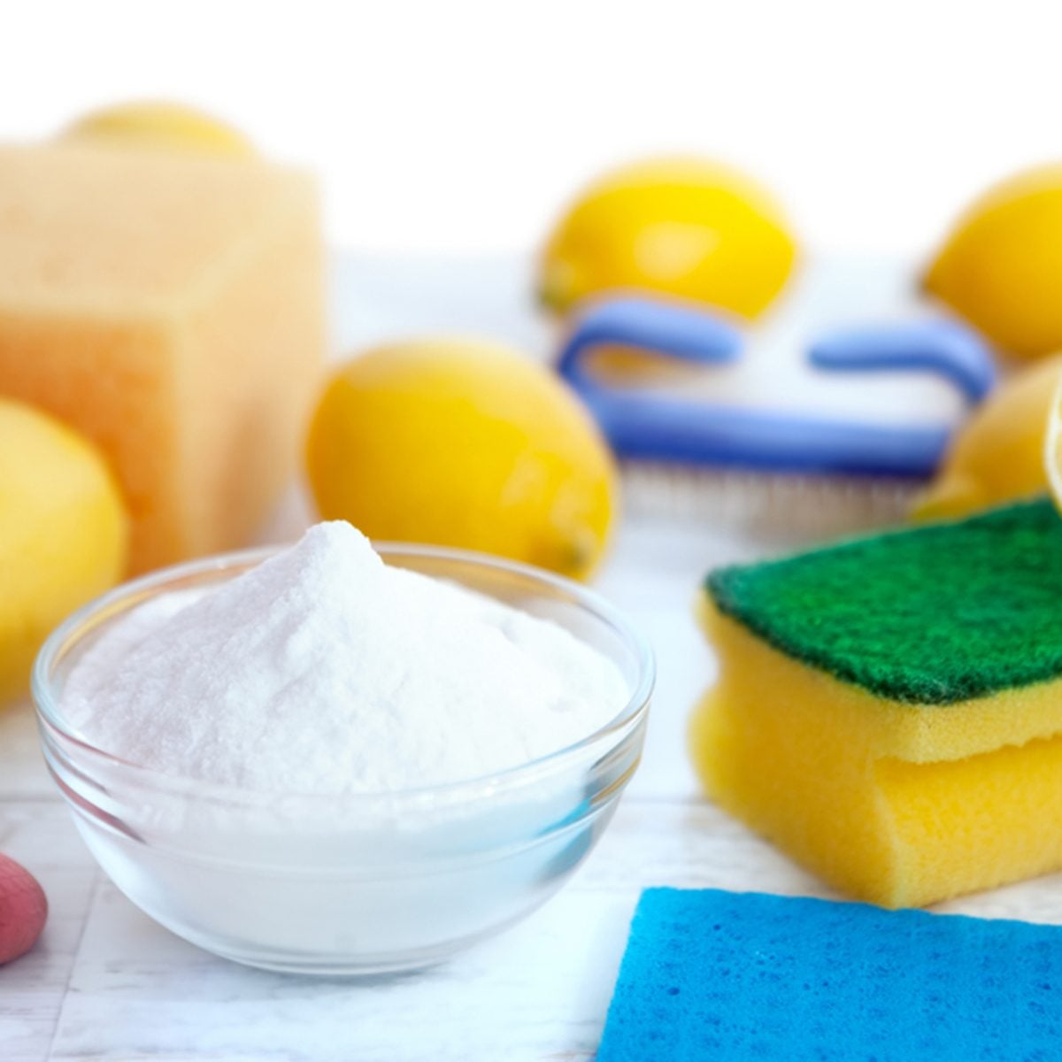 Cleaning accessories with baking soda,sponges and lemon on wooden surface