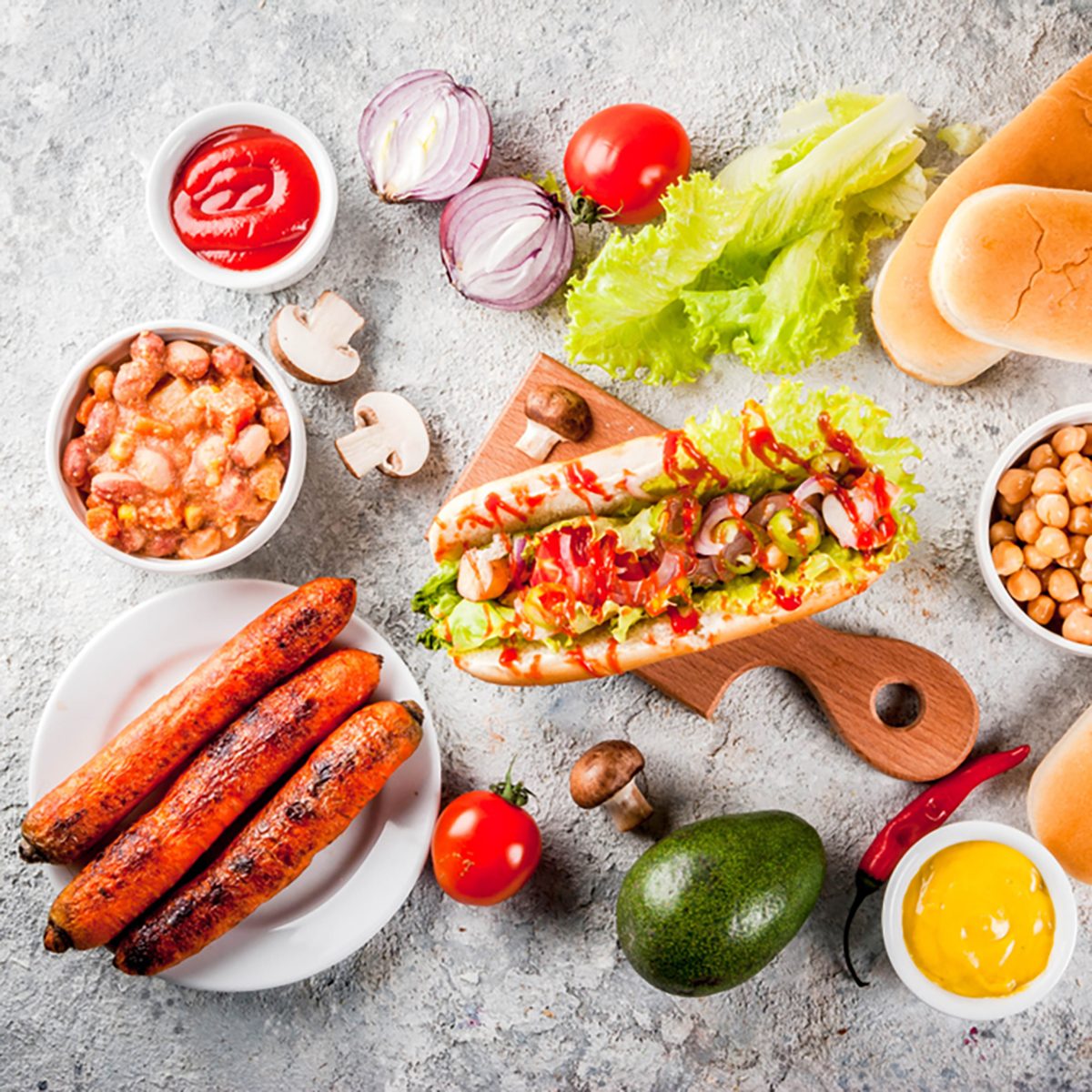 Ingredients for different homemade Vegan Carrot Hot Dogs, with fried onion, avocado, chili, mushrooms, tomatoes and beans