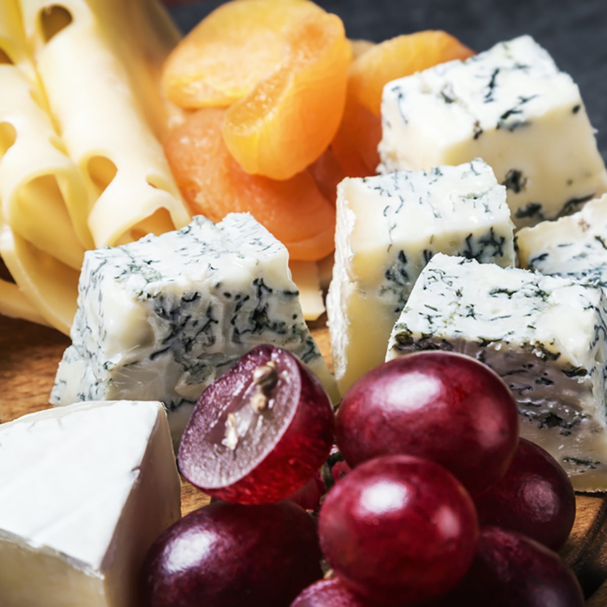 Cheese plate with fruits and nuts on a black background