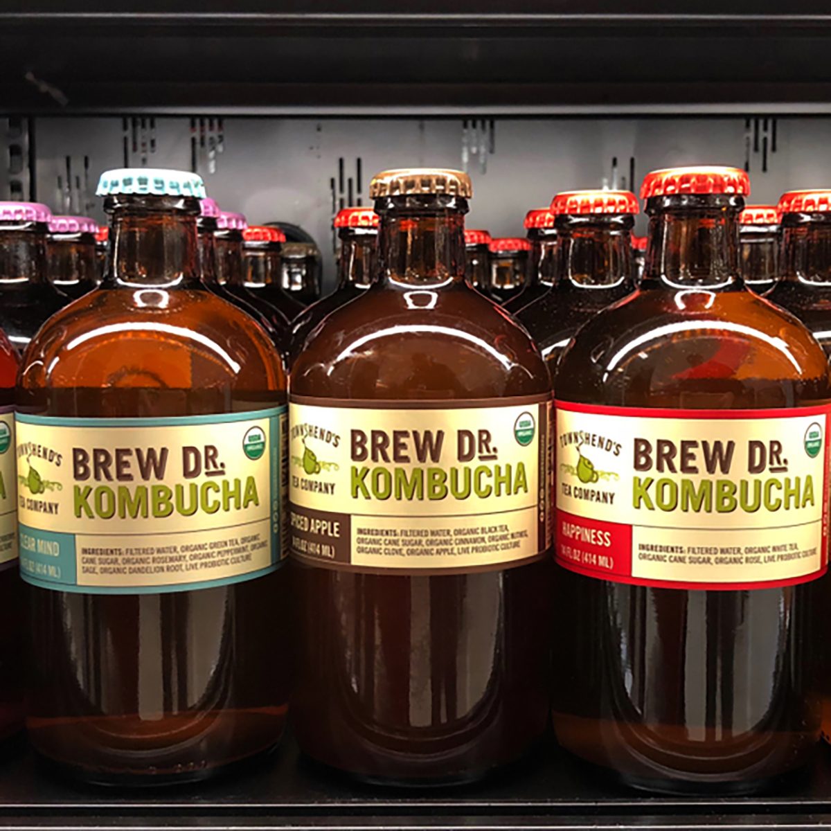 Grocery store shelf with bottles of Brew DR Kombucha in various flavors.