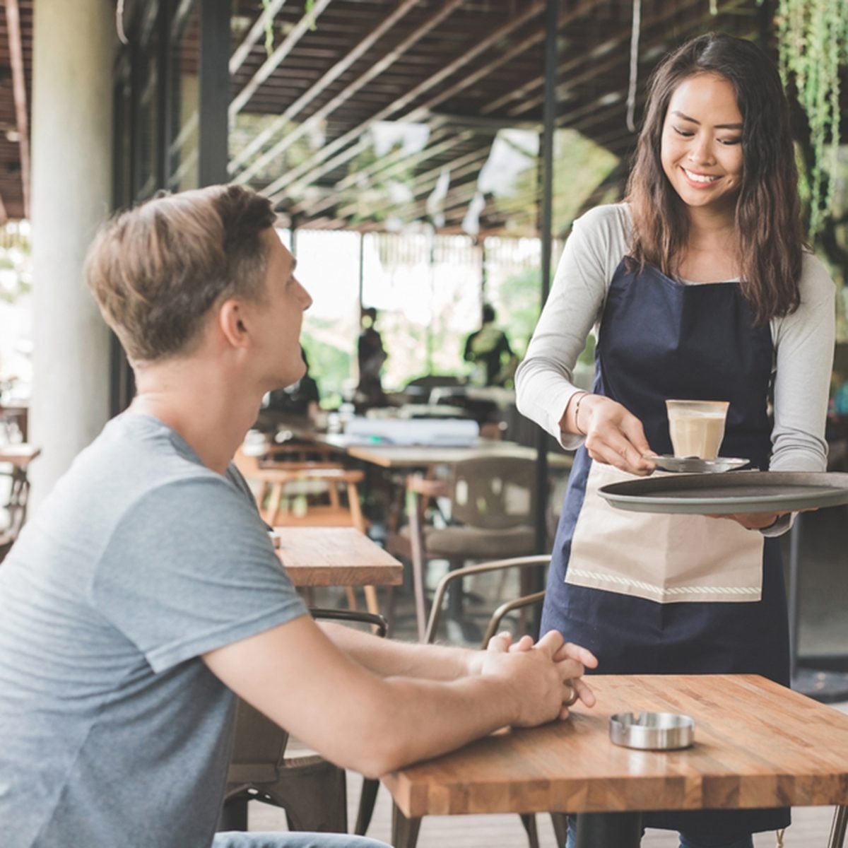 portrait of a female waitress serving coffee to a male customer