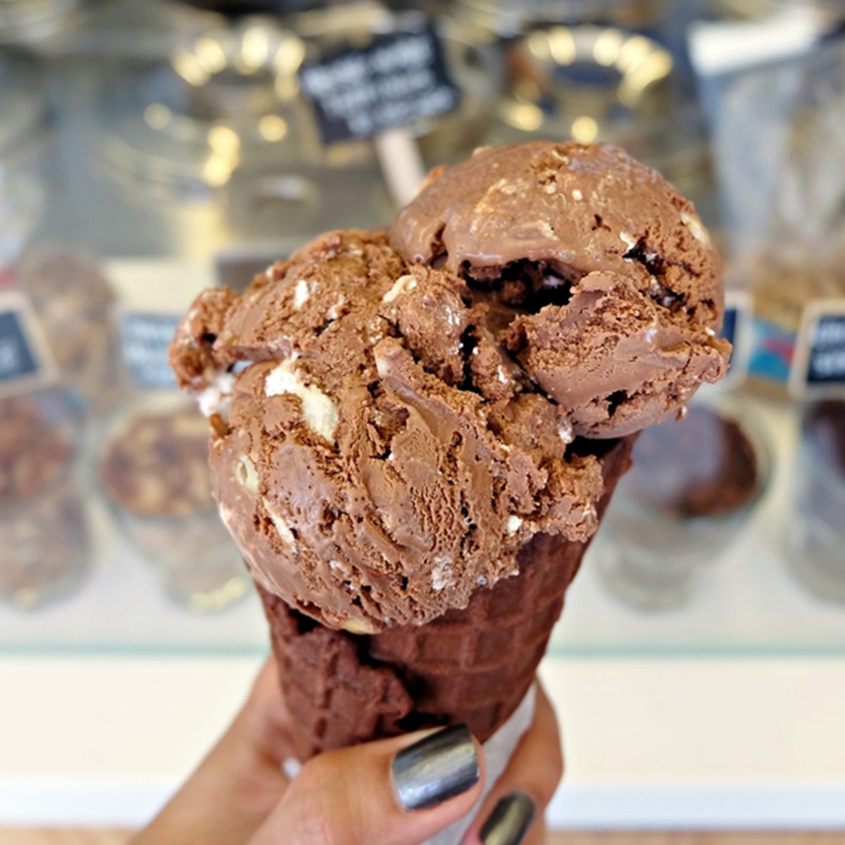 holding rocky road ice cream with chocolate waffle cone