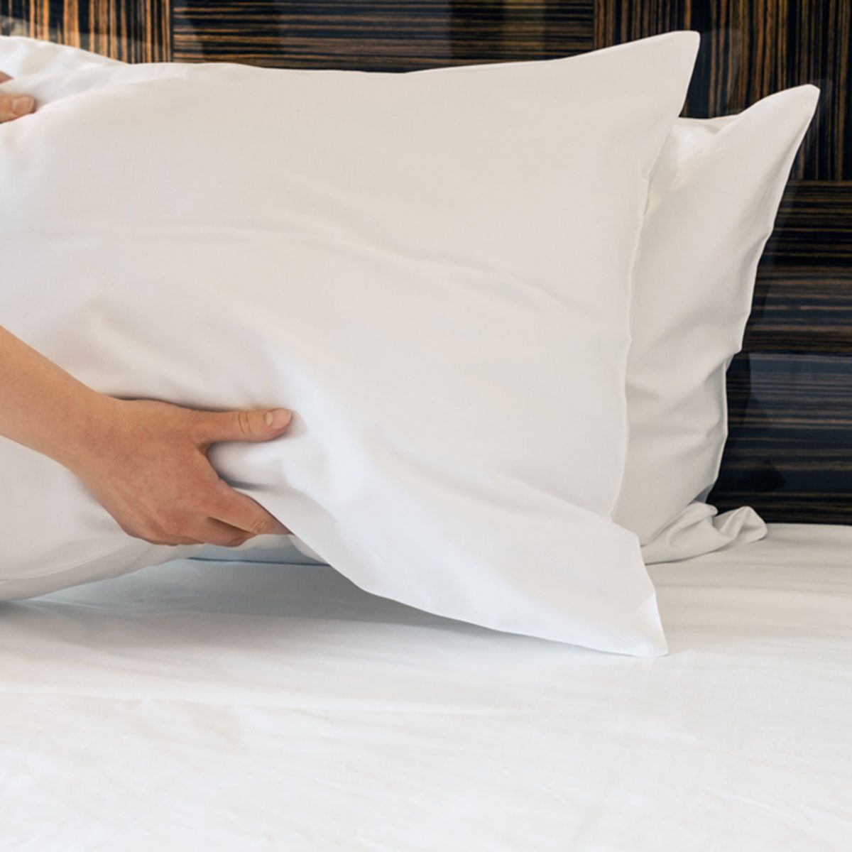 female hands corrected pillow on the bed.
