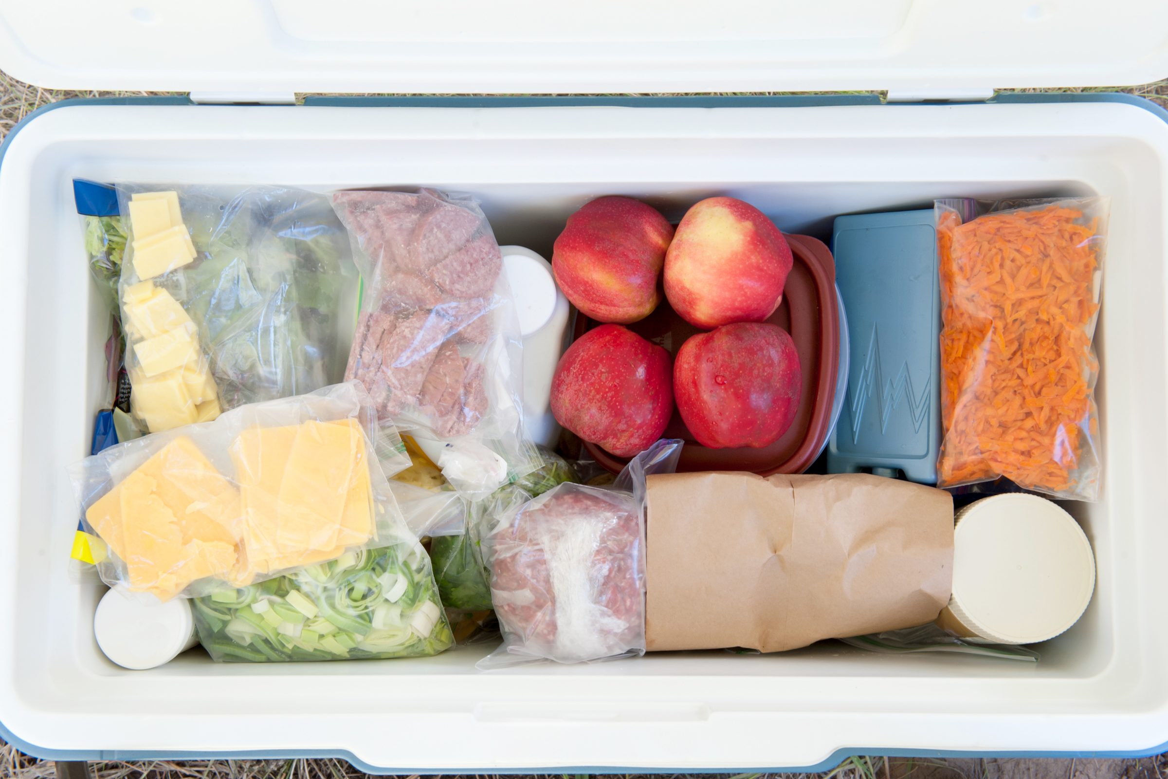 top view of a Packed Cooler for camping with apples, cheese and shredded carrots