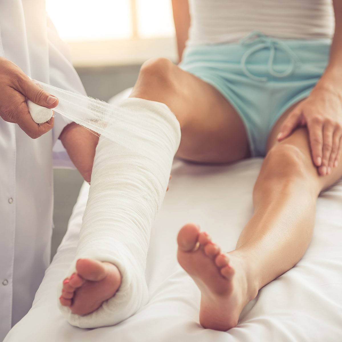 Cropped image of handsome doctor bandaging woman