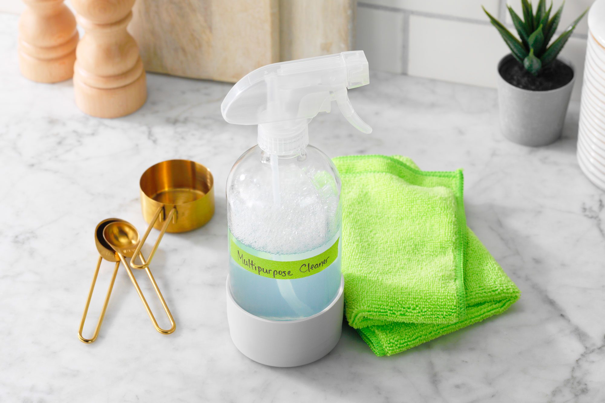 Homemade Cleaners Multipurpose Cleaner on a kitchen countertop next to measuring cups and microfiber cleaning cloth