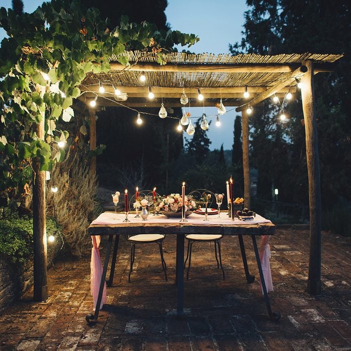 Decorated outdoor wedding table with flowers, lights and candles in rustic style