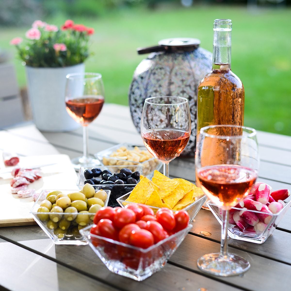 holiday summer brunch party table outdoor in a house backyard with appetizer, glass of rosé wine, fresh drink and organic vegetables