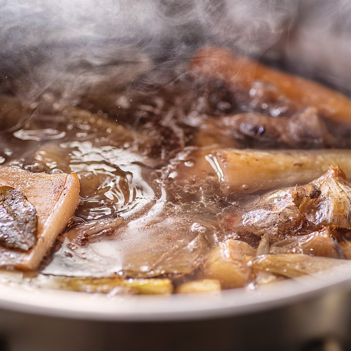 traditional beef broth with vegetable, bones and ingredients in pot