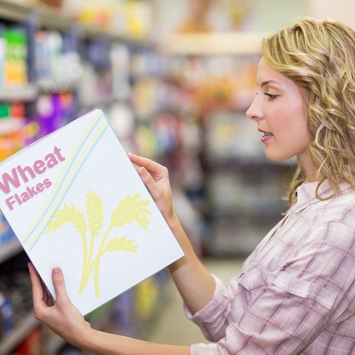 Side view of a pretty blonde woman reading a book in supermarket