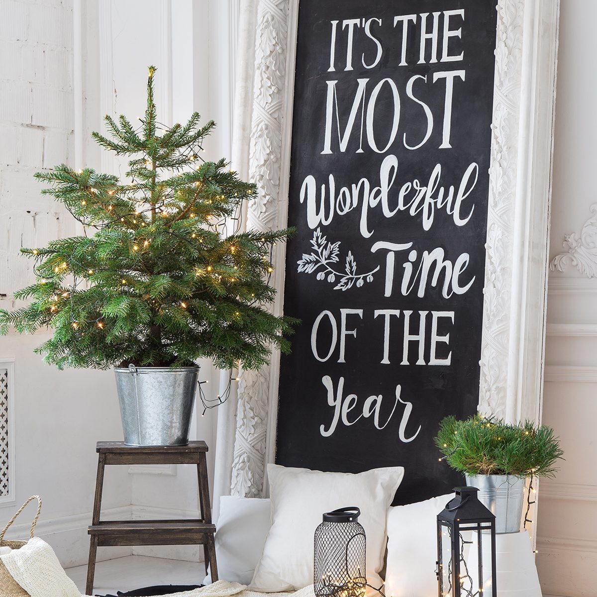 Luxurious, light interior in Scandinavian style with a frame with an inscription decorated with a Christmas tree, sheep skin and pillows.
