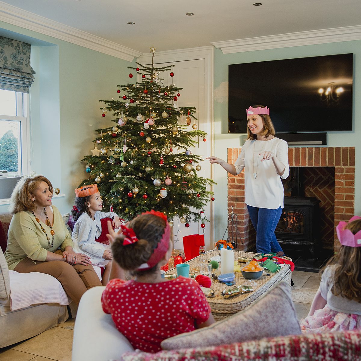 Family are playing charades at christmas time in the living room of their home. It