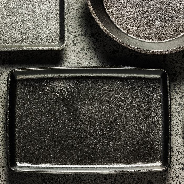 Various cast iron skillets and pans on dark background.