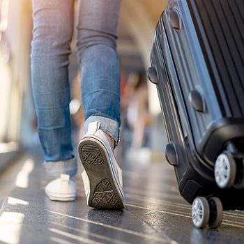 Woman traveler walking alone with suitcase bag. Travel weekend vacation trip.