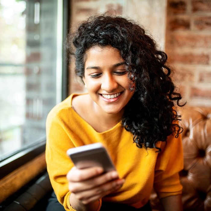 Young Indian woman using mobile phone at the bar
