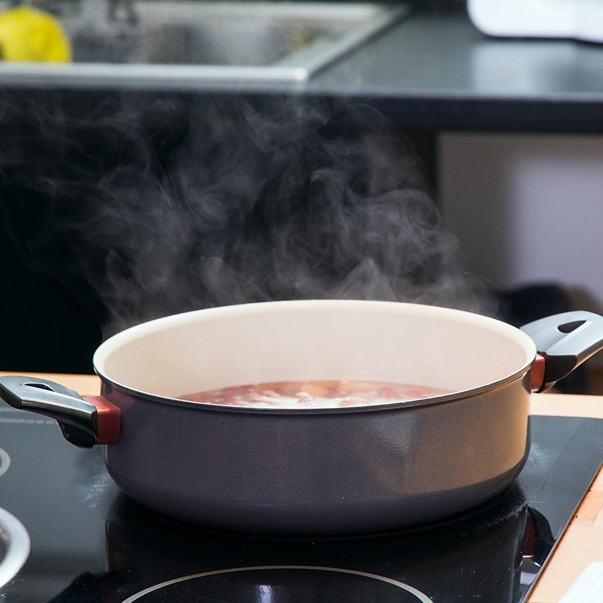 Saucepan with boiling clear soup on the plate