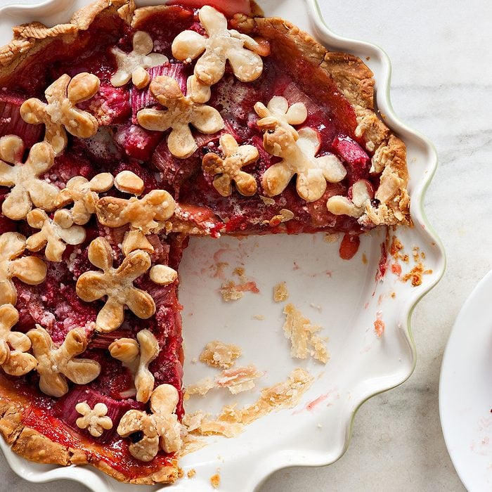 An overhead close up shot of a strawberry rhubarb pie and a slice.