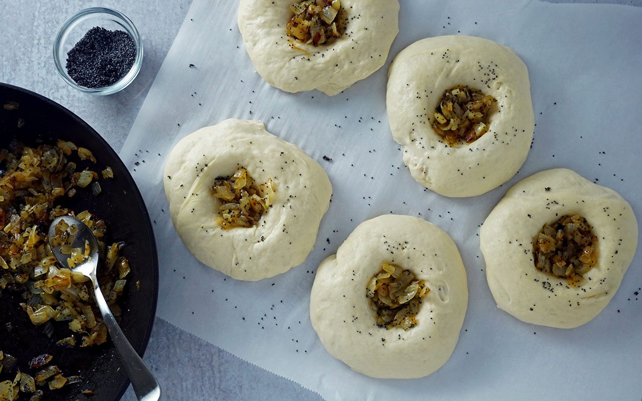 bialy dough formed, filled with onions and ready to bake