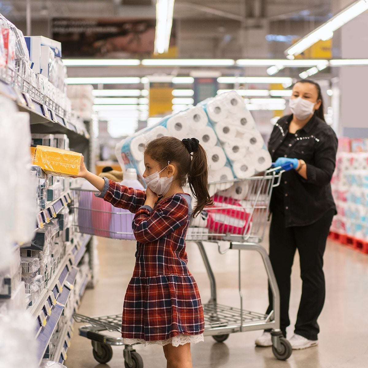 Portrait of a mature woman with her daughter wearing a protective mask shopping in a supermarket