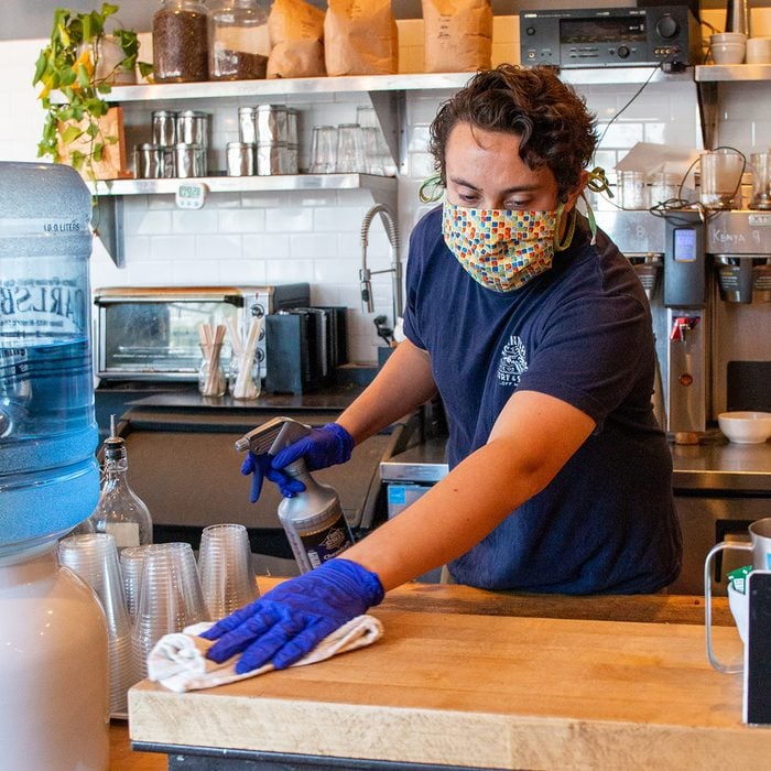 Man working in a coffee shop wearing a mask