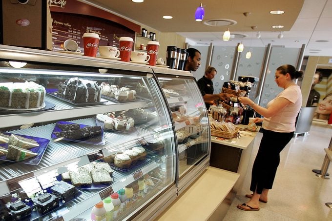 Female pays McCafe employee for her coffee drink beyond a pastry display case at a new McCafe located in a newly constructed McDonald's restaurant