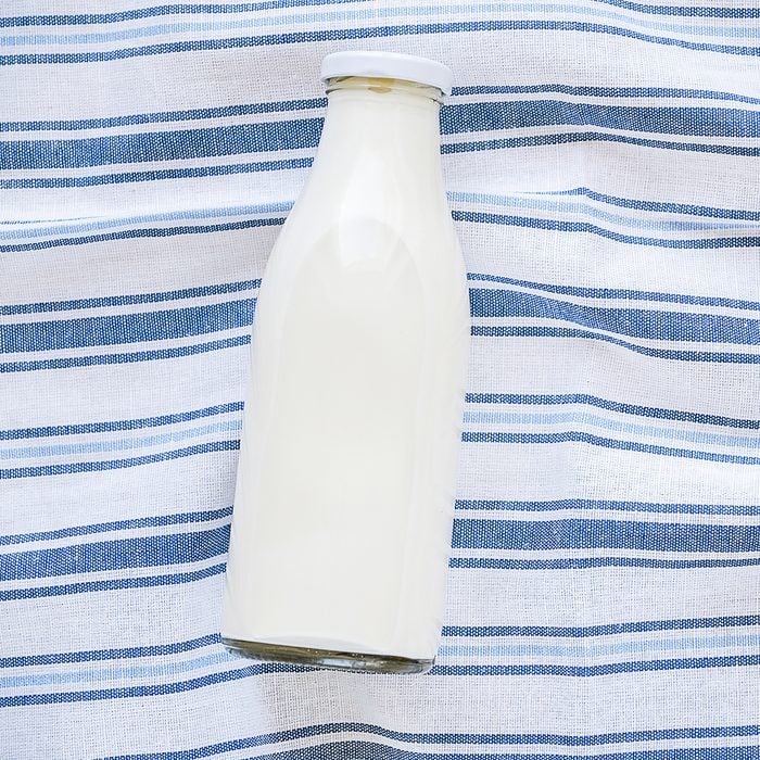 On a striped linen towel is a glass bottle of fresh milk. The concept of healthy organic, farm food. The view from the top. Copy space for text
