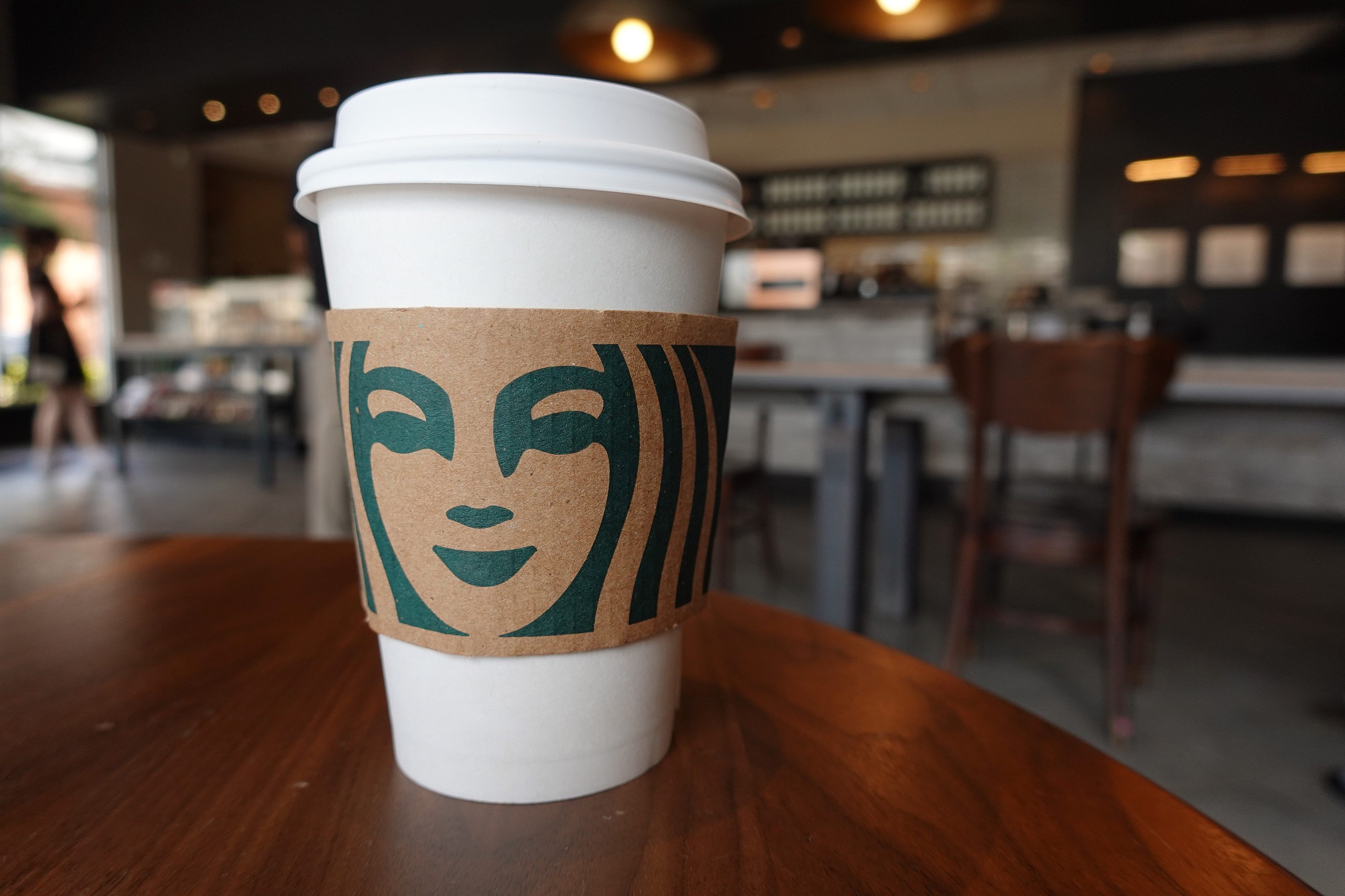 medicine ball starbucks drink cup sits on a table with the cafe out of focus in the background