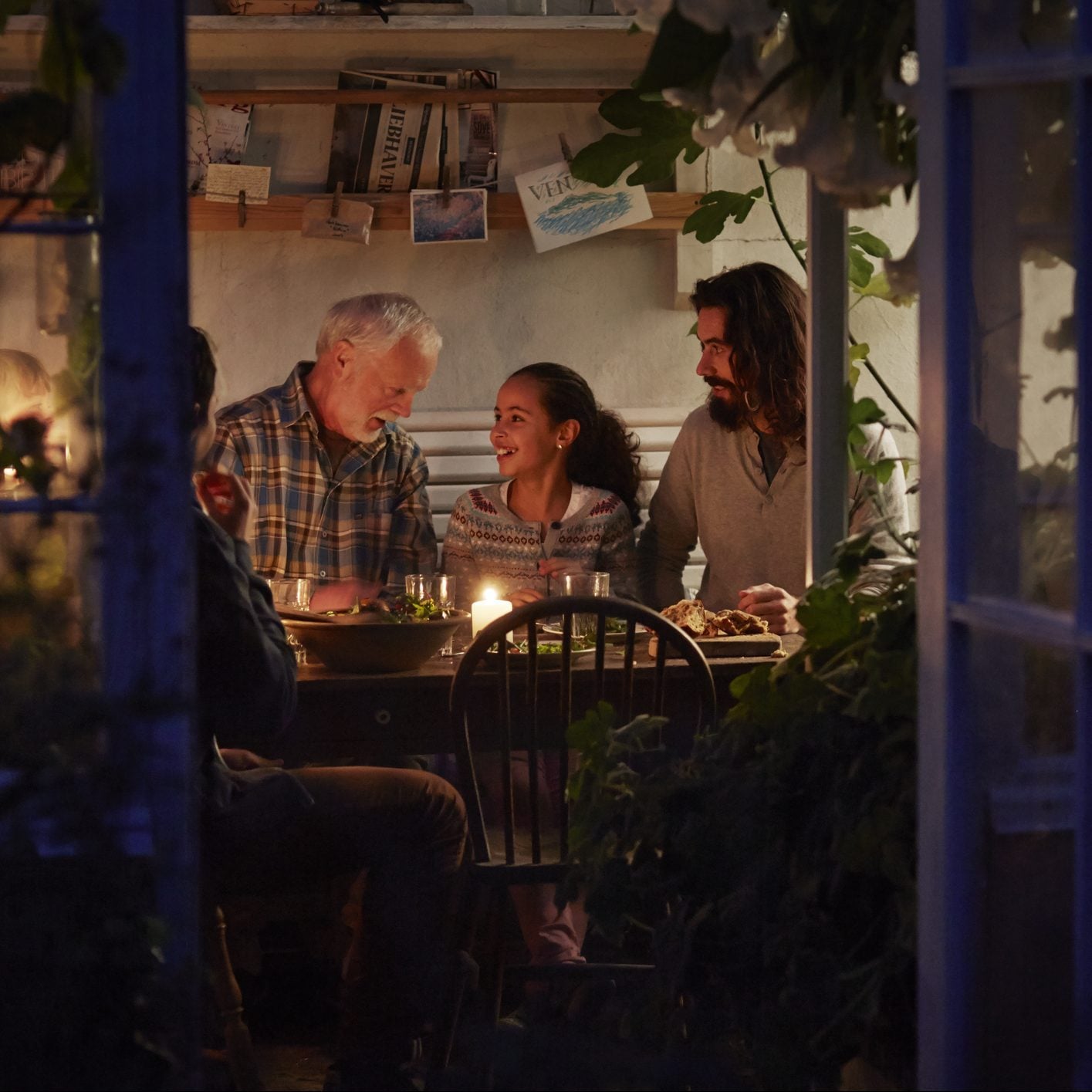 Grandfather telling a story at candle lit family dinner