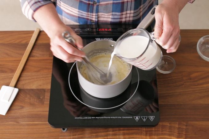 person pouring milk into gravy mixture