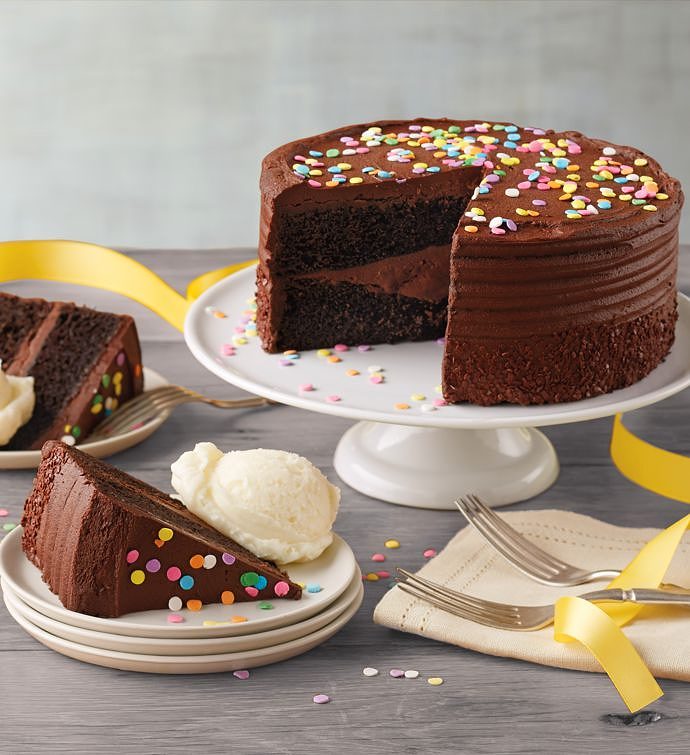 round chocolate cake on a white serving plate with a slice on a smaller plate next to it