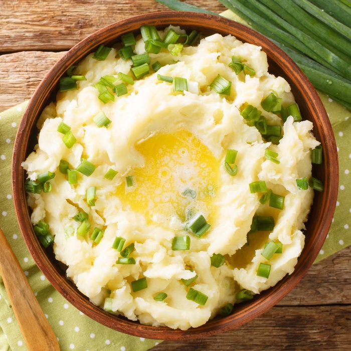 Irish Champ is a simple food made of potatoes, milk, green onions, butter close up in the bowl. Horizontal top view