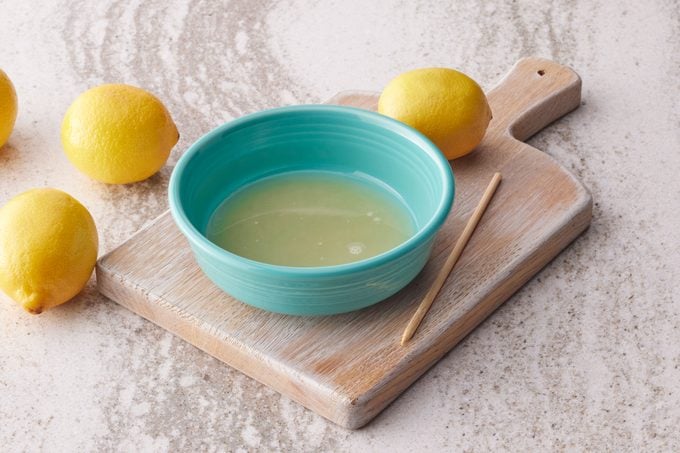 lemons and a small teal bowl of lemon juice