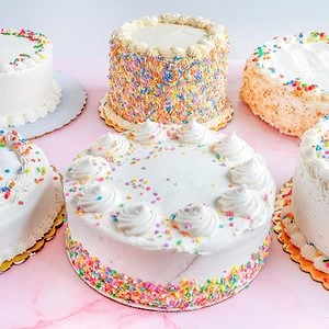 array of grocery store cakes on a pink background