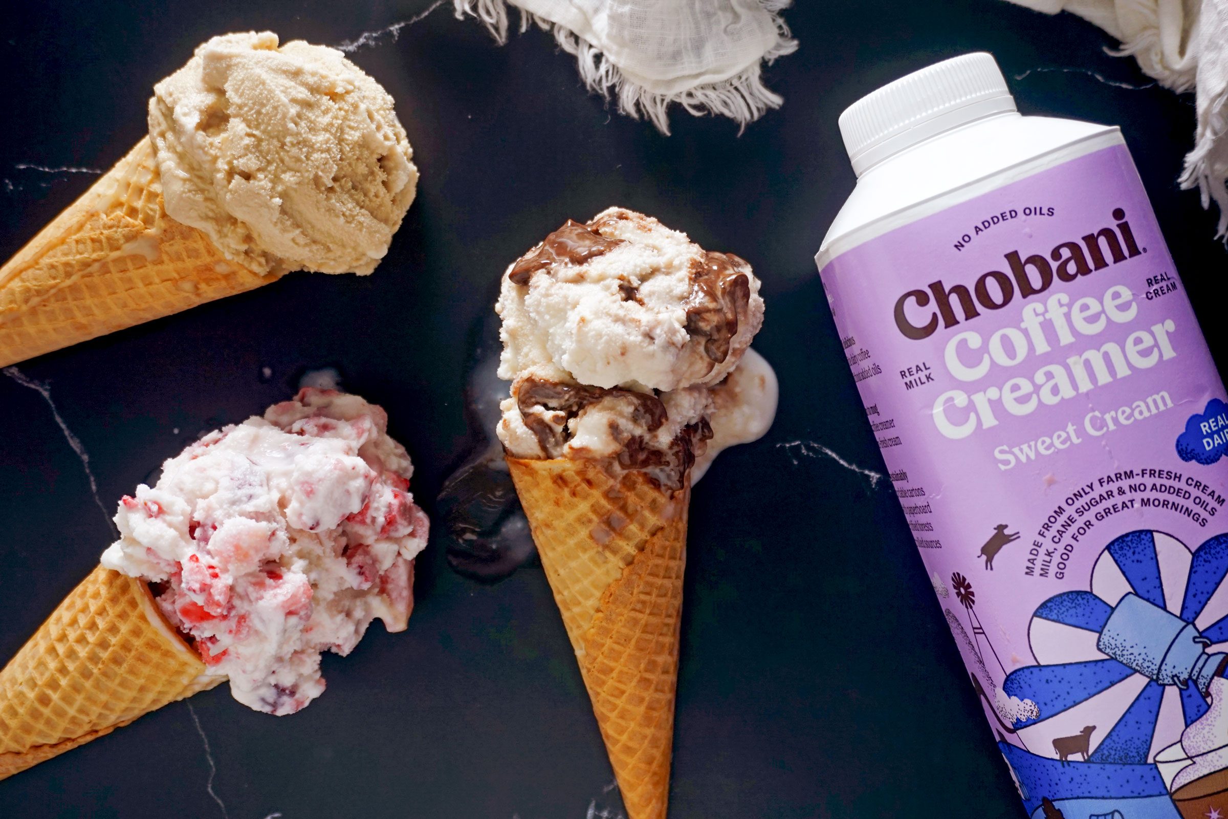 ice cream scooped into cones next to coffee creamer container on dark marble background