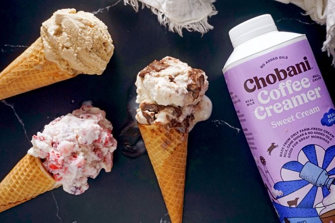 ice cream scooped into cones next to coffee creamer container on dark marble background