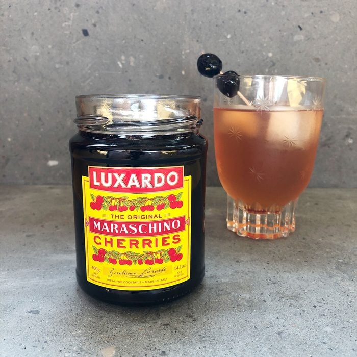 Luxardo cherry jars with a cocktail in the background