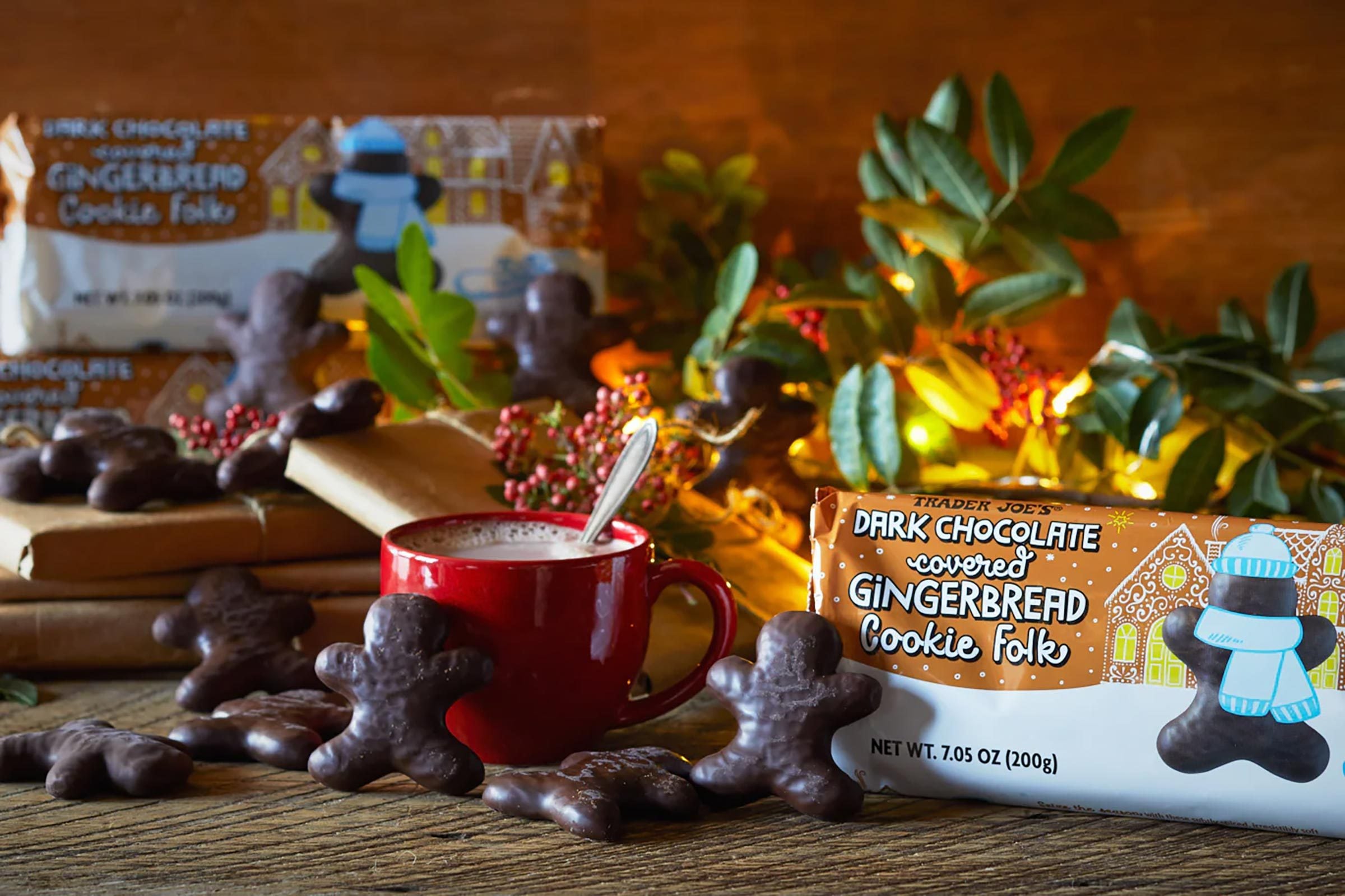 Dark Chocolate Gingerbread Cookie Folk with lights, greenery and wrapped packages, mug of hot chocolate and cookies scattered on surface