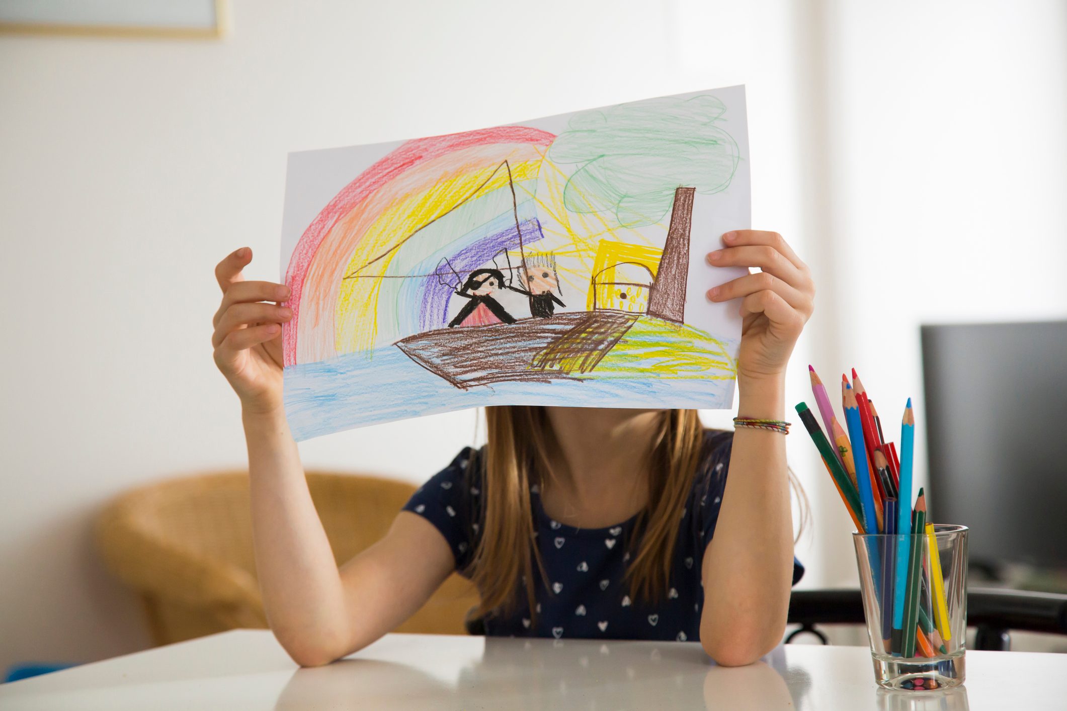 Little girl hiding behind her drawing
